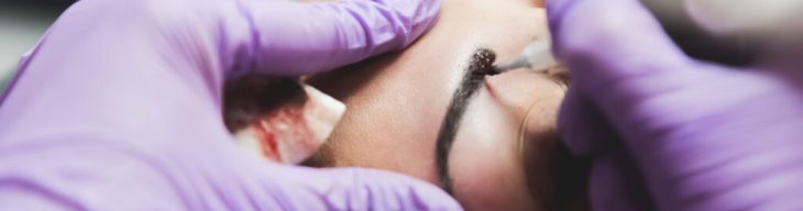 Close up of female patient on macro eyebrows make up treatment, she's bleeding while tattooing.